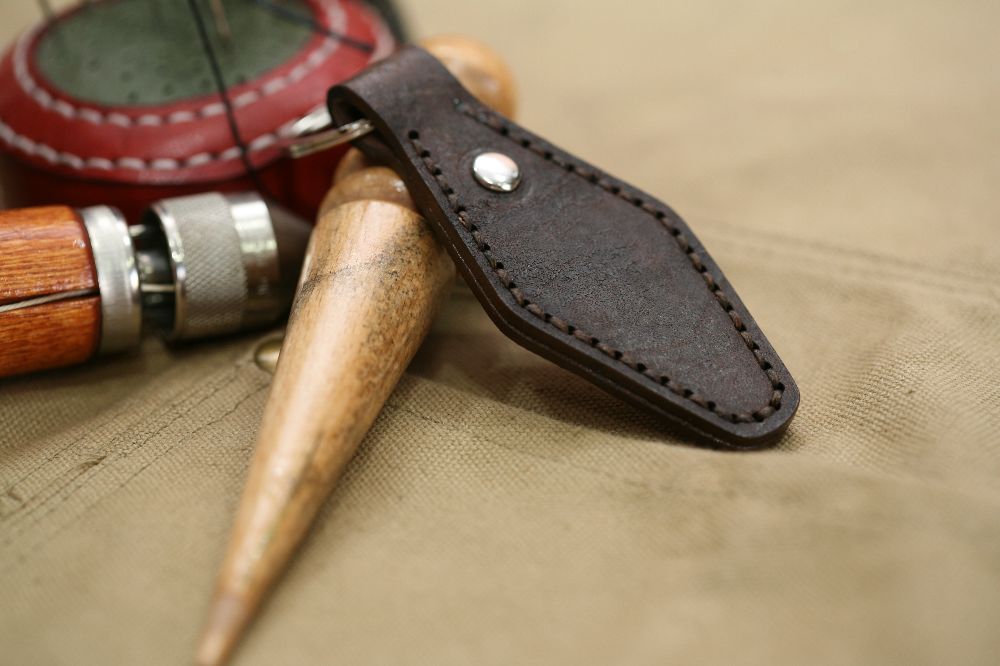 Handcrafted leather keyring with detailed stitching, available in brown and other colours