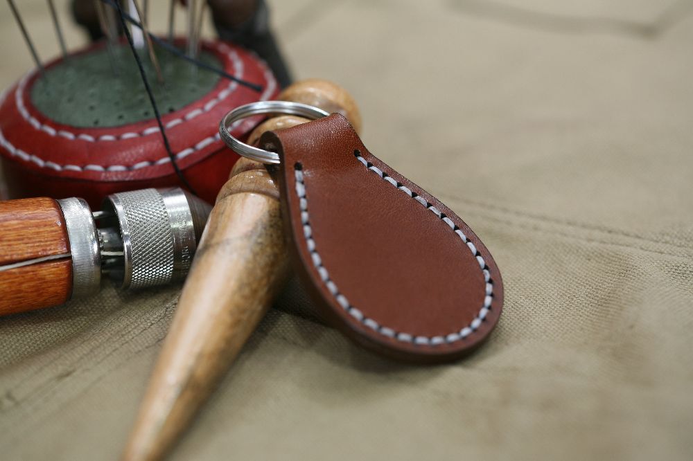 Handcrafted leather keyring with detailed stitching, available in brown and other colours