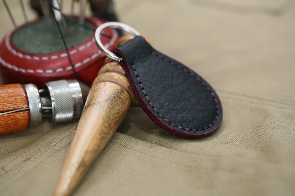 Handcrafted leather keyring with detailed stitching, available in brown and other colours